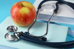 Medical stethoscope with apple and books.