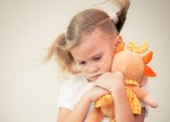 little girl cuddling orange soft toy