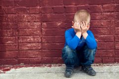 Crying Boy Sitting Near Red Brick Wall