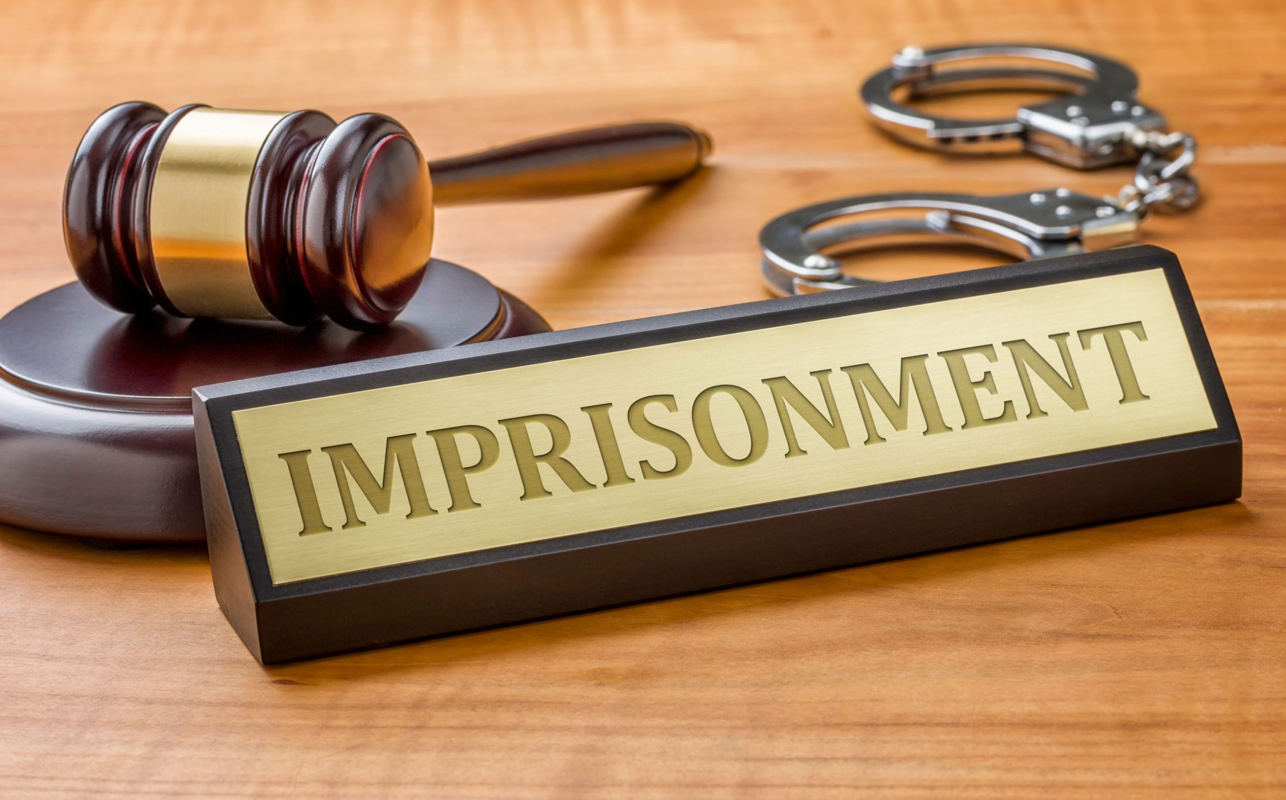 A gavel and a name plate engraved with the word imprisonment.