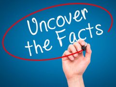 Man hand writing uncover the facts with black marker on visual screen. isolated on blue. business, technology, internet concept. stock image.